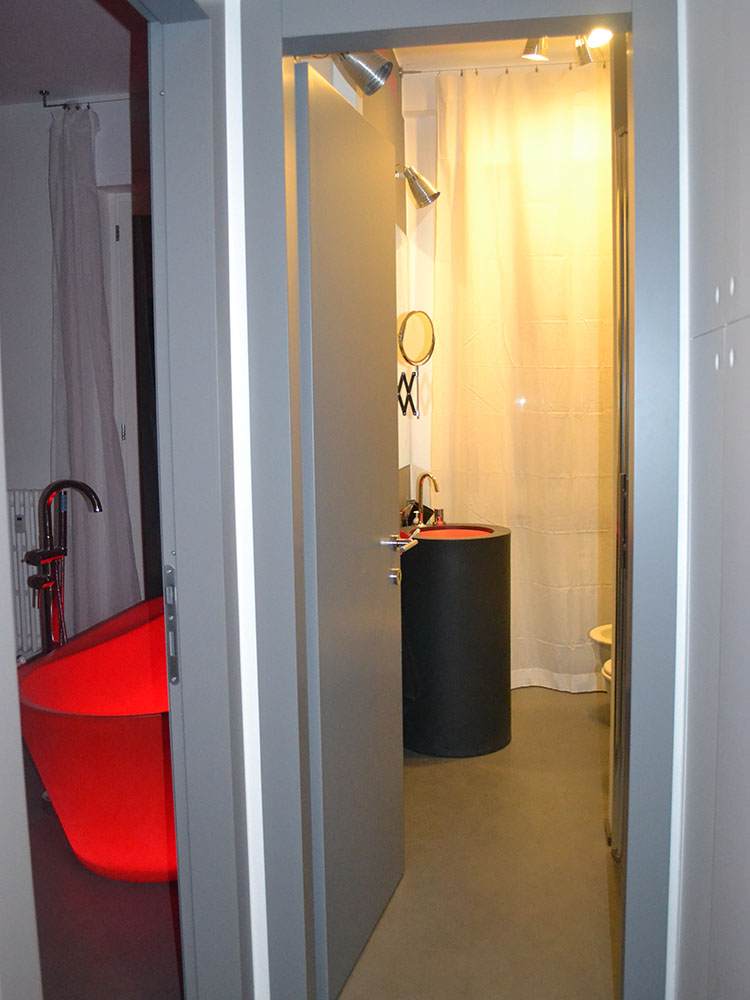 Bagno moderno con lavabo cilindrico nero, interno rosso e box doccia