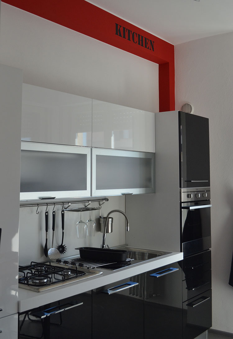 Cucina moderna lineare con basi nere lucide e pensili bianchi
