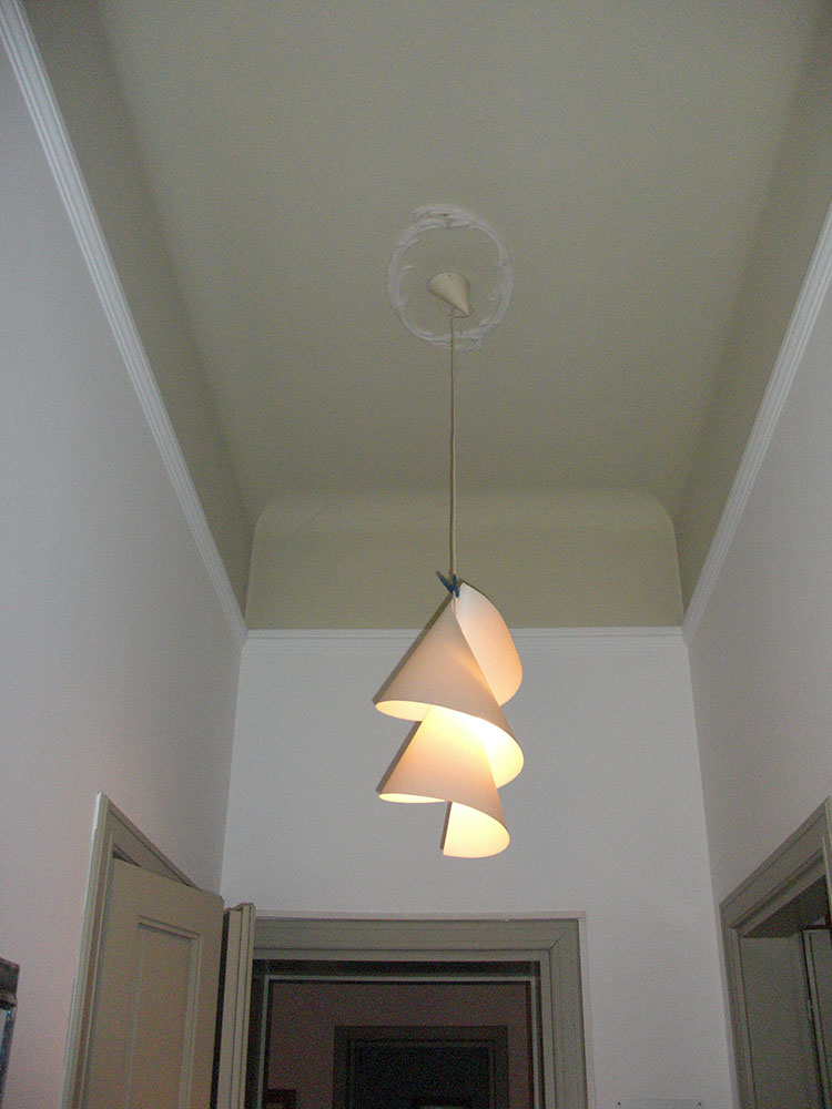 Lampada Willydilly di Ingo Maurer sospesa nel corridoio con soffitto a volta.