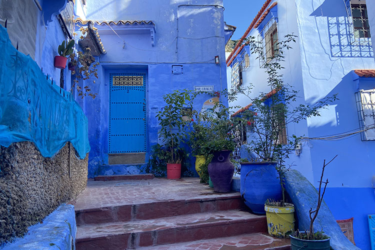 Scorcio della medina di Chefchaouen tra scale, porte decorate e facciate completamente dipinte di blu.